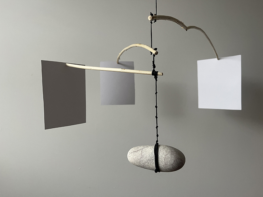 hand-made mobile with rock, sticks, paper