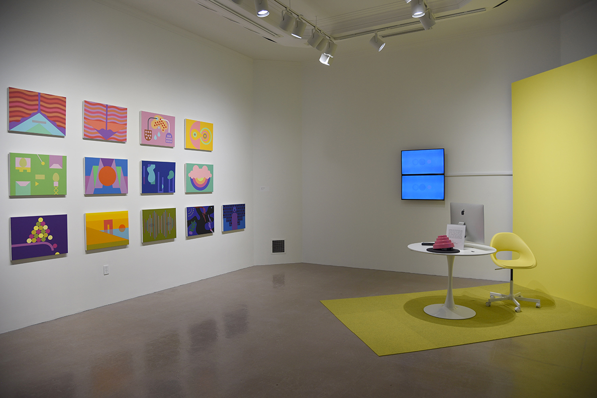 Installation image of Jennifer Marman and Daniel Borins: THX2020, with a wall of paintings across from a small table and chair with a computer monitor and a pink pyramid structure hat